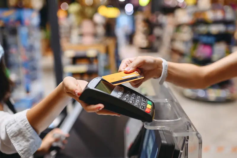 A hand swiping a card at payment terminal